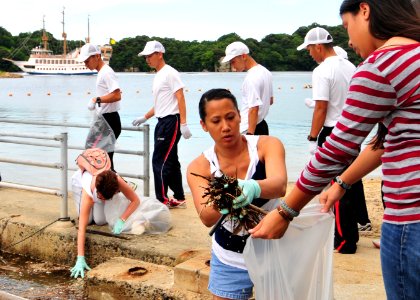 US Navy 110718-N-WJ771-126 Sailors assigned to Commander, Fleet Activities Sasebo help Japanese nationals remove trash from Kashimae Beach during a photo