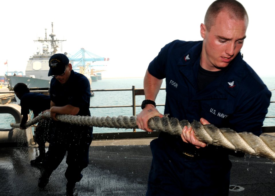 US Navy 110714-N-QL471-008 Boatswain's Mate 3rd Class Brandon Foor, right, and Seaman Roderick Goudy heave a mooring line on the fantail aboard the