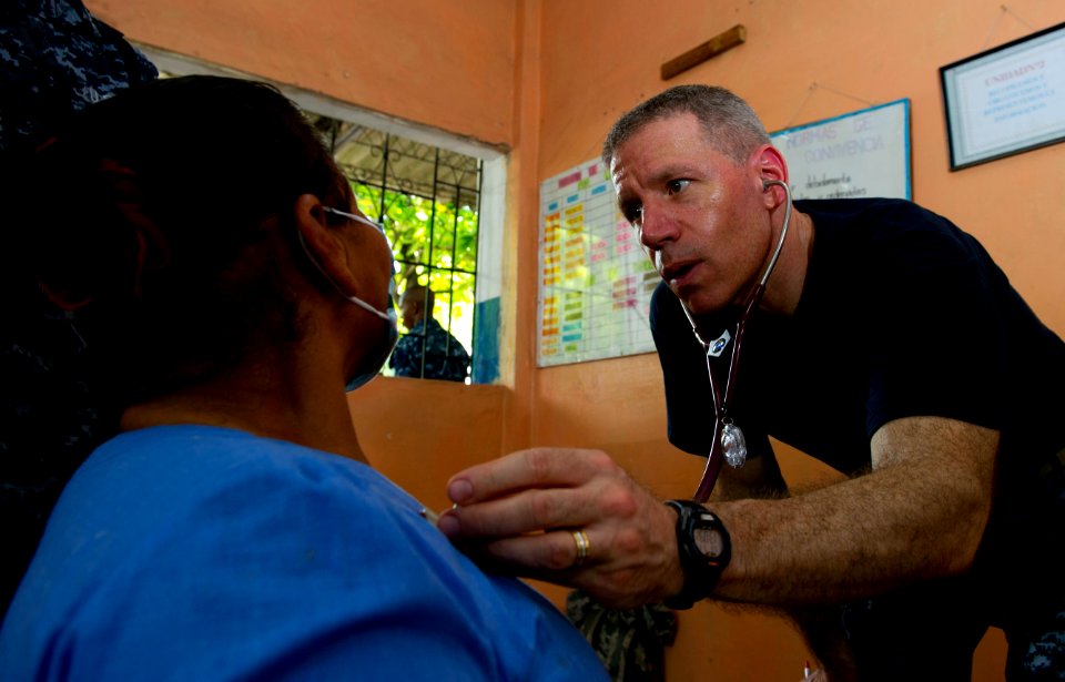 US Navy 110714-N-RM525-101 Capt. Michael Mazzilli, from Montrose, N.Y., examines a woman's breathing at a pre-screening vital signs station during