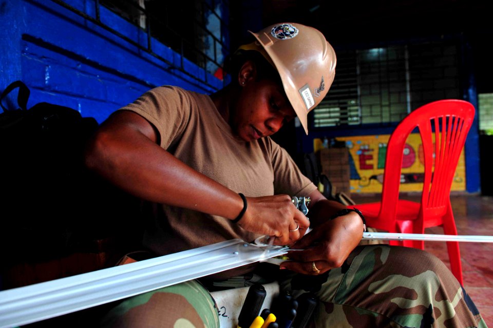 US Navy 110717-F-NJ219-023 Construction Electrician 2nd Class Raynita Garner, from Mobile, Ala., assembles a ceiling fan at Escuela Canton Miravall