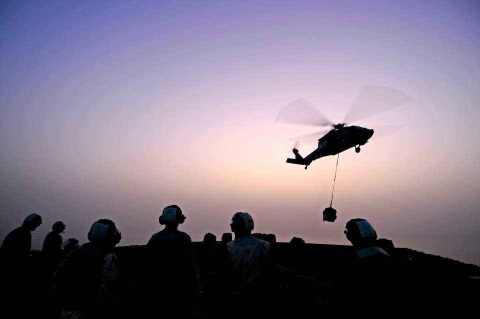 US Navy 110717-N-RC734-371 Sailors stand by as an MH-60S Sea Hawk helicopter delivers cargo to USS Comstock (LSD 45) during a vertical replenishmen