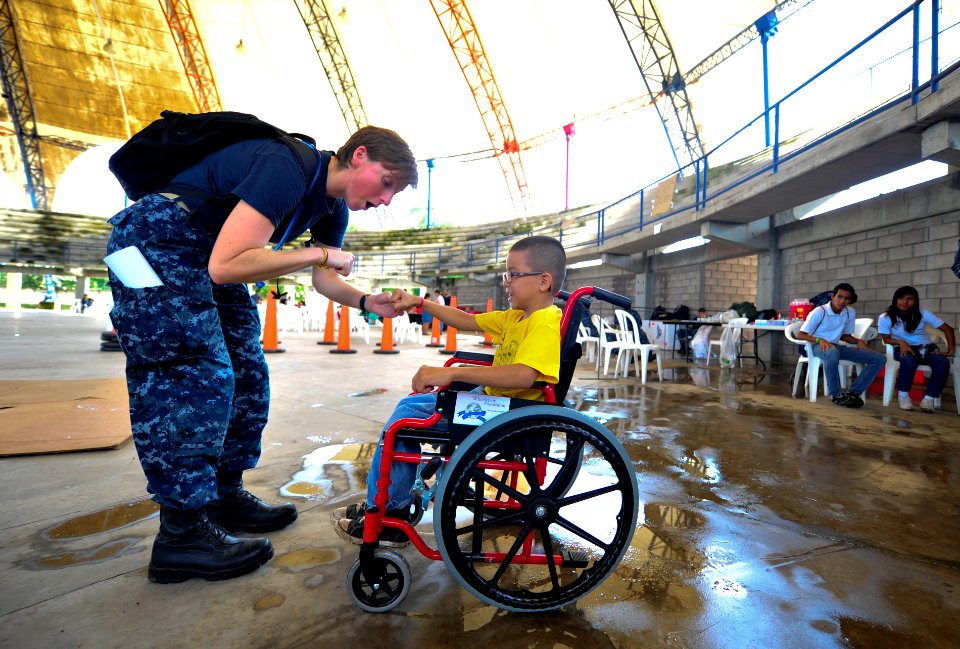 US Navy 110718-N-RM525-156 Lt. Erinn Gelakoska, from St. Louis, fist bumps a Salvadoran child who just received a new wheelchair during a Continuin