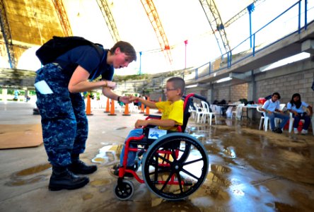 US Navy 110718-N-RM525-156 Lt. Erinn Gelakoska, from St. Louis, fist bumps a Salvadoran child who just received a new wheelchair during a Continuin photo