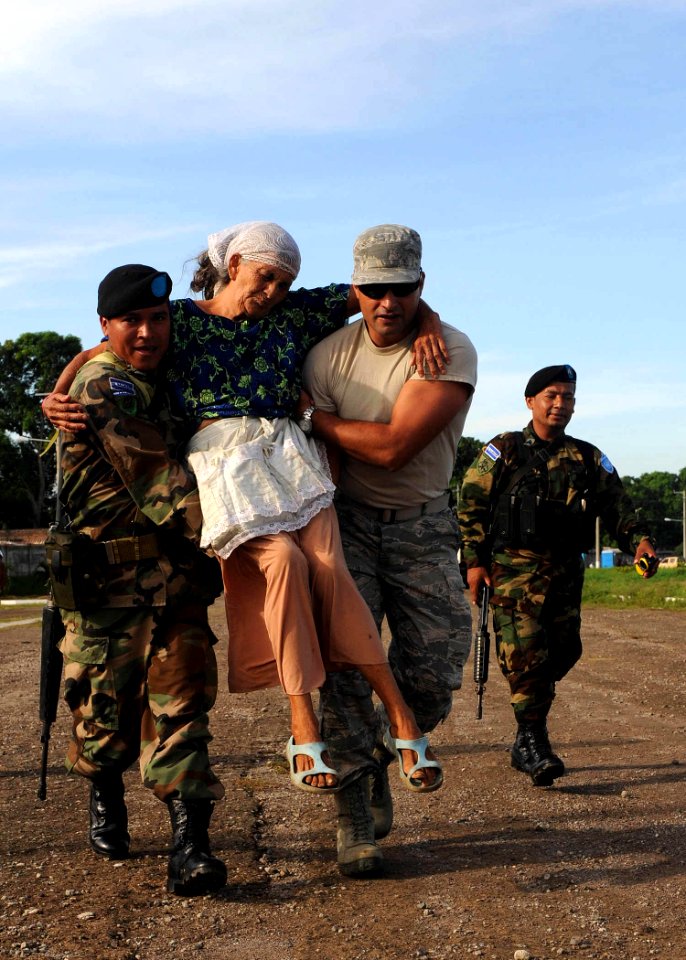 US Navy 110719-F-ET173-021 Senior Airman Cesar Salgado-Diaz, from Bogota, Colombia, and a Salvadoran soldier carry a woman from a waiting area to a
