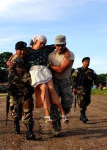 US Navy 110719-F-ET173-021 Senior Airman Cesar Salgado-Diaz, from Bogota, Colombia, and a Salvadoran soldier carry a woman from a waiting area to a