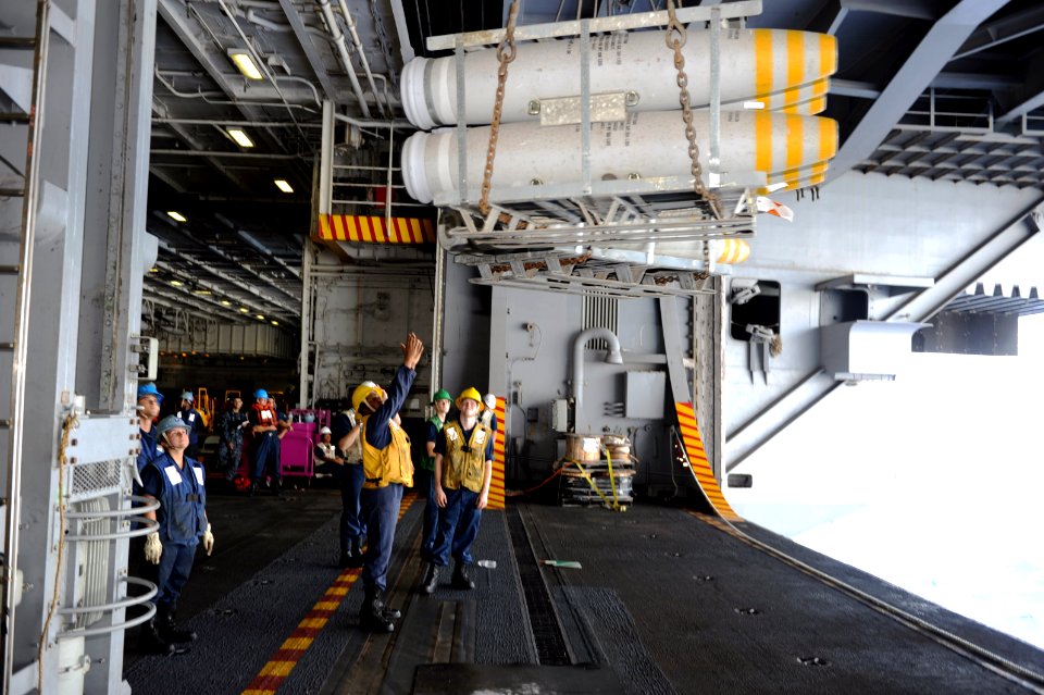 US Navy 110721-N-AU622-062 Boatswain's Mate 3rd Class Amber Rudolph signals to take ordnance aboard USS Dwight D. Eisenhower (CVN 69) during an amm
