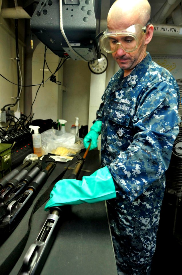 US Navy 110722-N-EE987-008 Personnel Specialist 3rd Class Vasile Mesaros, from Las Vegas, cleans a Mossberg shotgun in the armory aboard the aircra