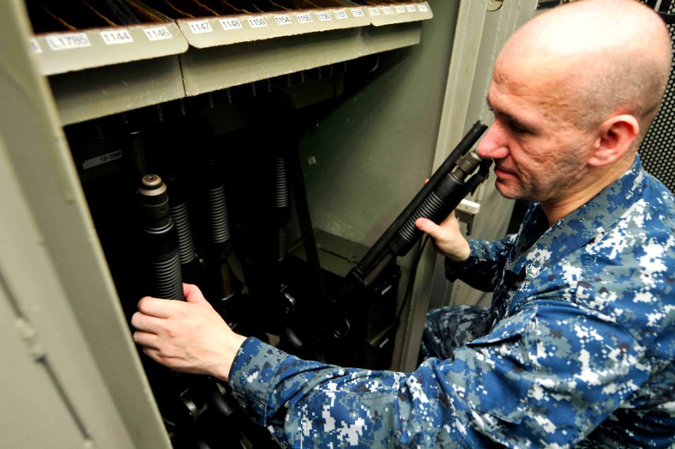 US Navy 110722-N-EE987-034 Personnel Specialist 3rd Class Vasile Mesaros, from Las Vegas, stows Mossberg shotguns in the armory aboard the aircraft