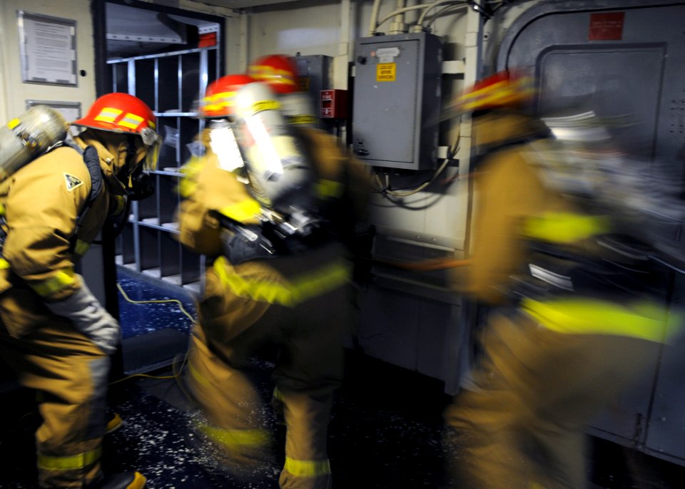 US Navy 110720-N-BK435-089 Sailors assigned to the submarine tender USS Frank Cable (AS 40) break through the door to ship's laundry during a fire