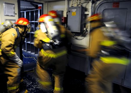 US Navy 110720-N-BK435-089 Sailors assigned to the submarine tender USS Frank Cable (AS 40) break through the door to ship's laundry during a fire
