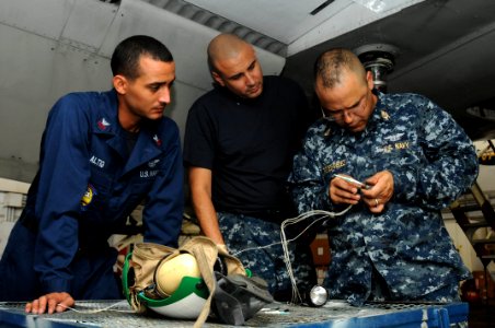 US Navy 110721-N-SP676-172 Aviation Electrician 1st Class Carlos Altig, left, and Aviation Electrician 2nd Class Adam Valverde observe Chief Aviati