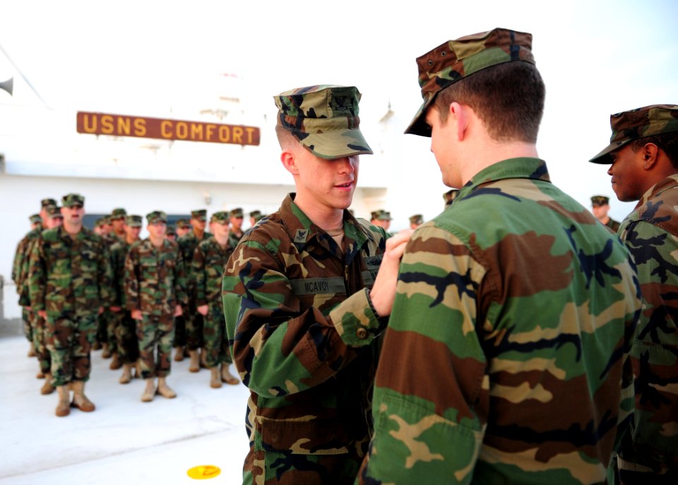 US Navy 110720-N-QD416-096 Master-at-Arms 2nd Class Brendan McAvoy pins an Enlisted Expeditionary Warfare Specialist device on Master-at-Arms Seama