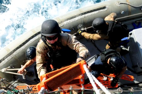 US Navy 110721-N-IO627-103 A Sailor climbs from a rigid-hull inflatable boat to the weather deck of the guided-missile destroyer USS Curtis Wilbur