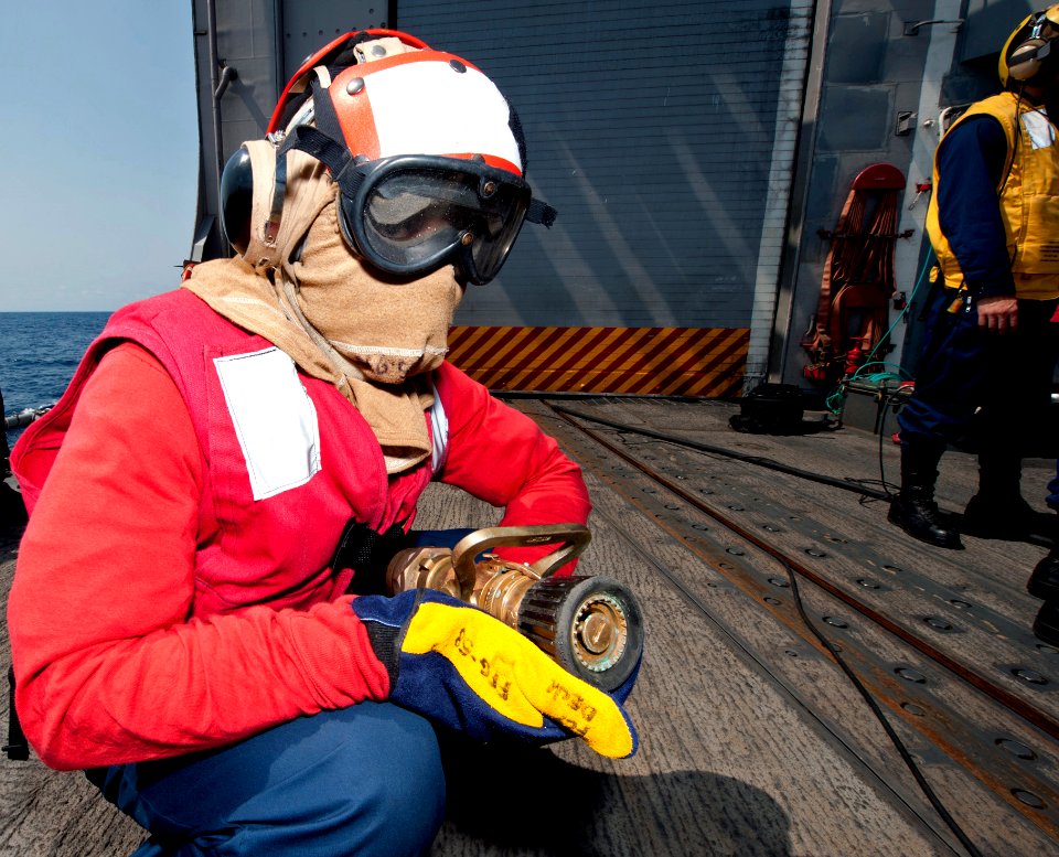 US Navy 110726-N-OV802-156 Ship's Serviceman Seaman Jarvis Jones serves as the nozzleman of a hose team while participating in a helicopter crash