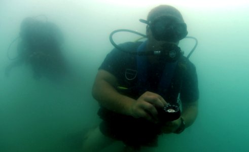 US Navy 110722-N-XD935-247 Navy Diver 2nd Class Justin McMillen checks his underwater compass as he makes his way to a designated area during joint