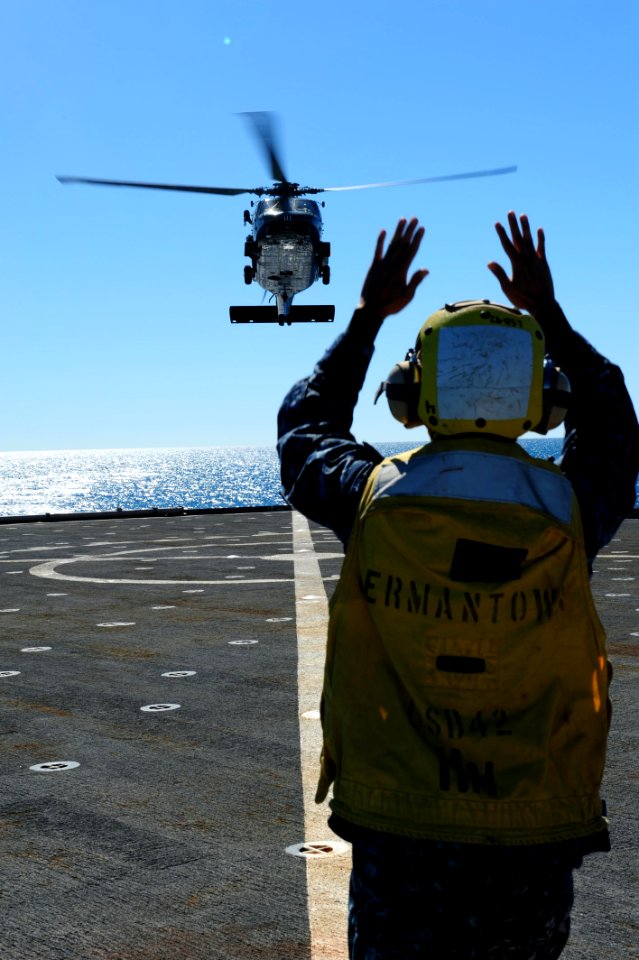 US Navy 110721-N-WA347-014 Boatswain's Mate 2nd Class Dennis Castro directs an MH-60S Sea Hawk helicopter