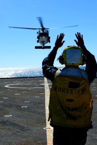 US Navy 110721-N-WA347-014 Boatswain's Mate 2nd Class Dennis Castro directs an MH-60S Sea Hawk helicopter