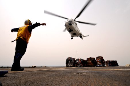 US Navy 110721-N-YM590-082 Boatswain's Mate 3rd Class Jean Guerra signals a Puma helicopter to release it's cargo hook on the flight deck of the gu