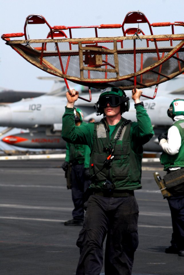 US Navy 110727-N-GL340-026 viation Electrician's Mate 2nd Class Thomas Allen carries a jet intake screen to an aircraft on the flight deck of USS R
