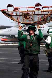 US Navy 110727-N-GL340-026 viation Electrician's Mate 2nd Class Thomas Allen carries a jet intake screen to an aircraft on the flight deck of USS R