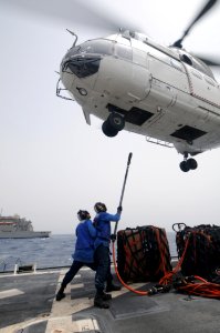US Navy 110725-N-XQ375-414 Boatswain's Mate 3rd Class Jeff Rashley, left, spots Boatswain's Mate Seaman C.L. Barnes Jr. as he hooks a cargo net to