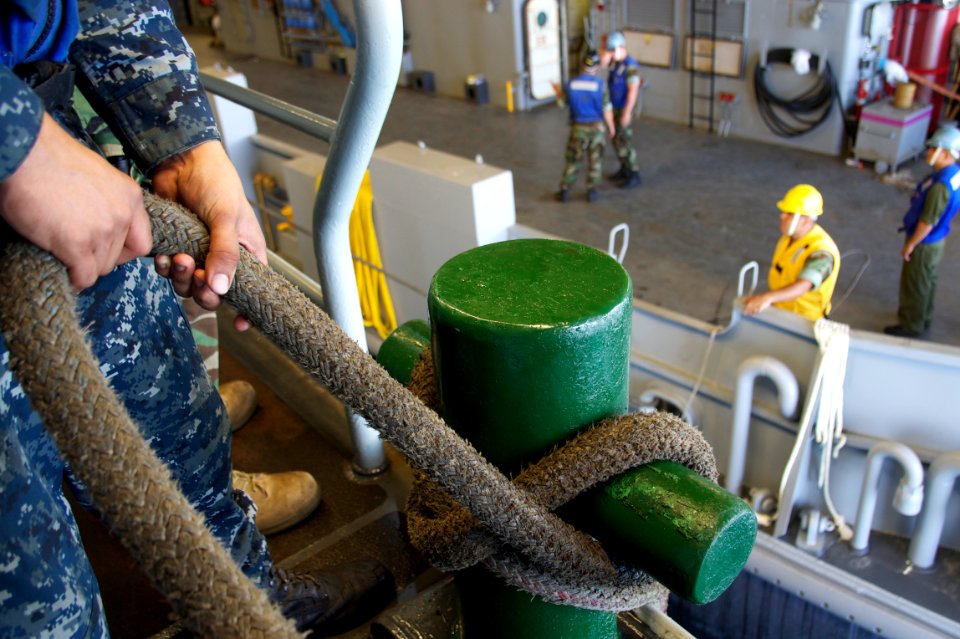 US Navy 110725-N-ZC343-260 Line handlers tighten down lines on a landing craft utility (LCU) in the well deck of the amphibious assault ship USS Bo