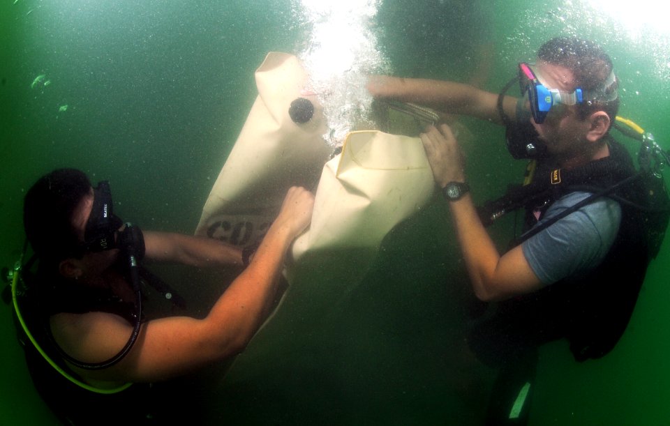 US Navy 110727-N-XD935-079 Navy Diver 3rd Class Bryan Myers, left, assists Antonio Sosa in releasing air out of an underwater lift bag during joint