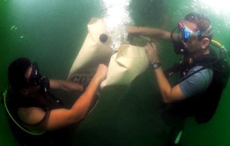 US Navy 110727-N-XD935-079 Navy Diver 3rd Class Bryan Myers, left, assists Antonio Sosa in releasing air out of an underwater lift bag during joint photo