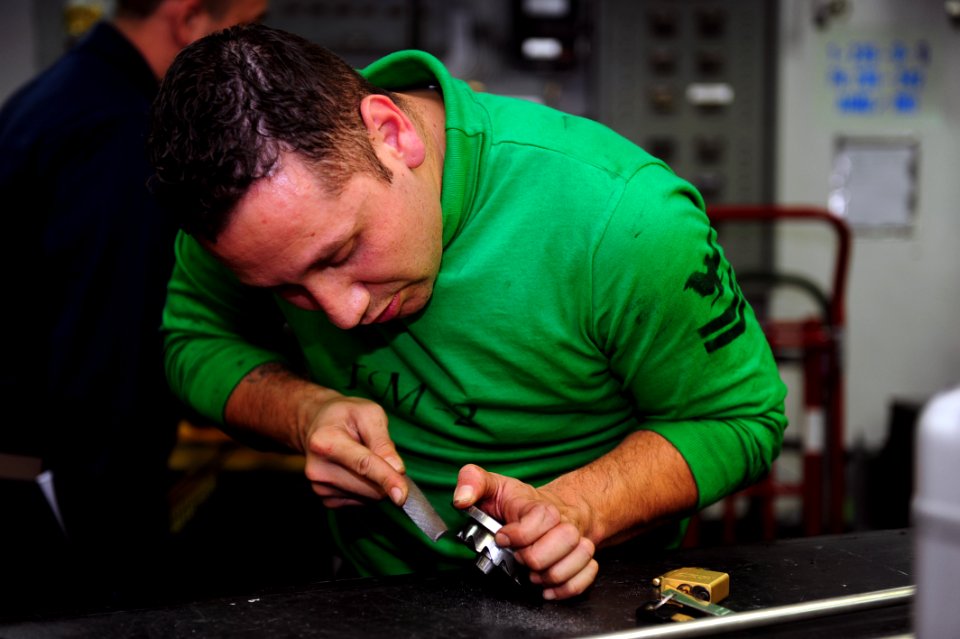 US Navy 110726-N-OI955-072 Aviation Machinist's Mate 2nd Class Angel Arellano files down parts of a starter plate from an F-A-18 Super Hornet jet e