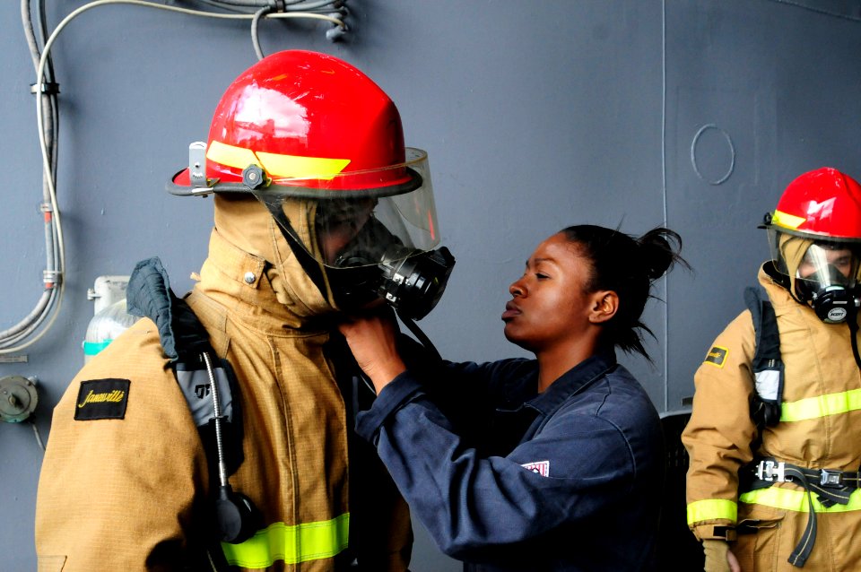 US Navy 110729-N-WV964-024 Damage Controlman Fireman Jasmine Bly checks a Sailor's firefighting ensemble during basic damage control training aboar