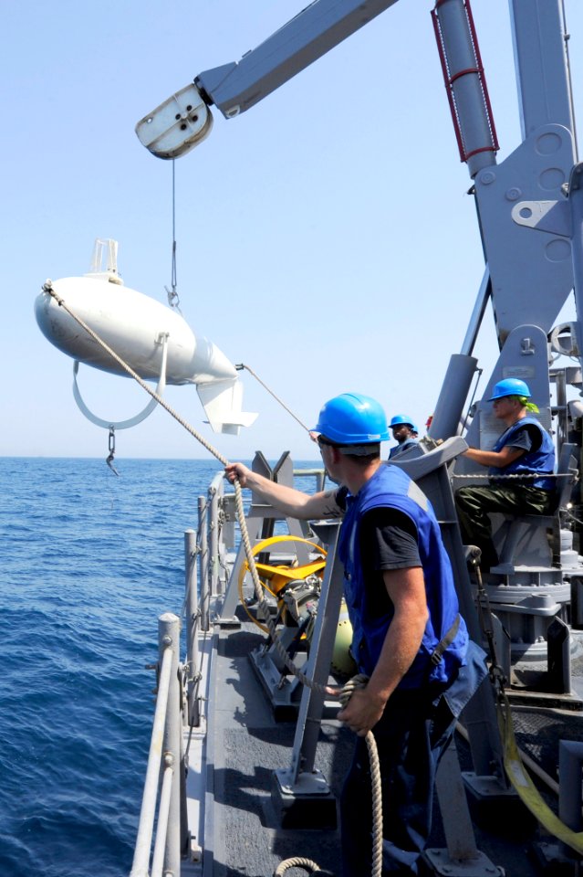 US Navy 110723-N-WL435-036 Sailors aboard USS Gladiator (MCM 11) maintain positive control of a mine sweeping floatation device as it is craned abo