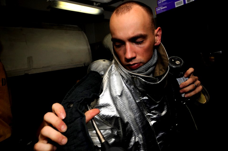 US Navy 110727-N-ZZ999-036 Aviation Boatswain's Mate (Handling) 3rd Class Marc Trietch dons a self-contained breathing apparatus during a hangar ba