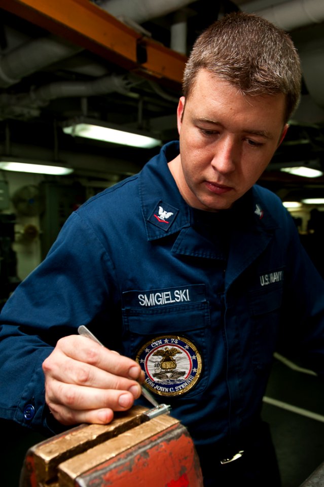 US Navy 110803-N-BT887-022 Machinery Repairman 3rd Class Chris Smigielski, from Daytona Beach, Fla., adds pins to a lock aboard the Nimitz-class ai
