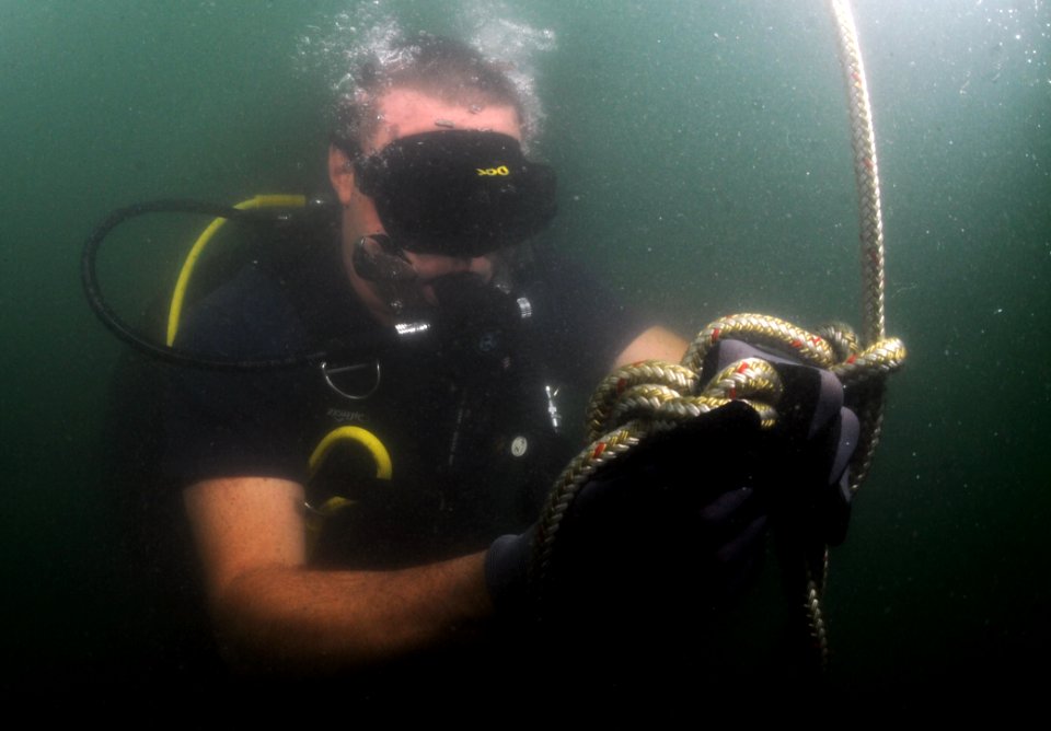 US Navy 110728-N-XD935-017 Chief Hospital Corpsman Nathanael Warren ies a Bowline knot in a circle search line during joint diving search operation