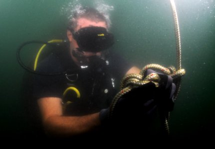 US Navy 110728-N-XD935-017 Chief Hospital Corpsman Nathanael Warren ies a Bowline knot in a circle search line during joint diving search operation photo