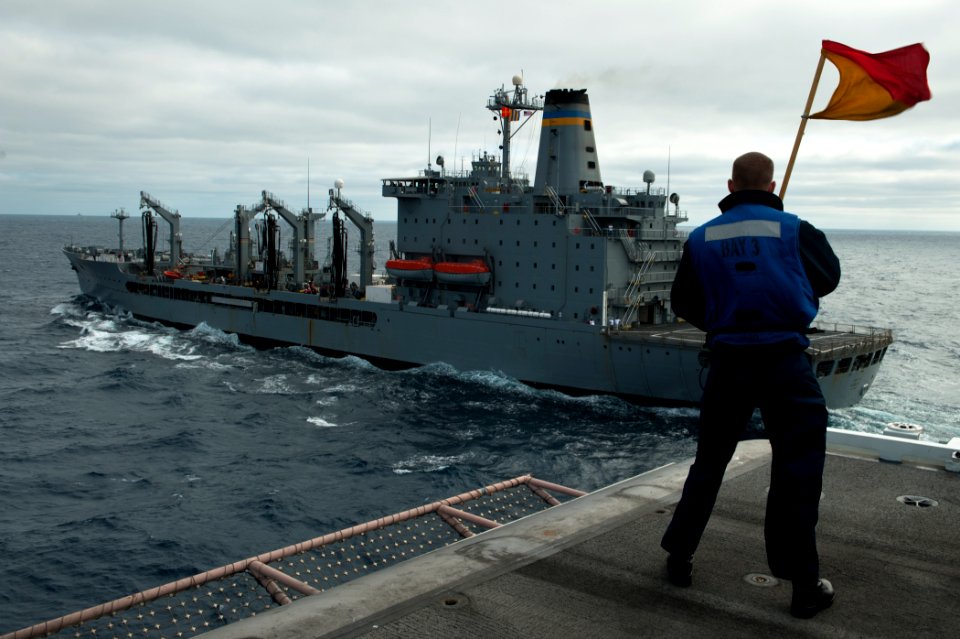 US Navy 110730-N-BT887-074 uartermaster Seaman Tyler Shear carries the Oscar flag during a replenishment at sea aboard USS John C. Stennis (CVN 74)