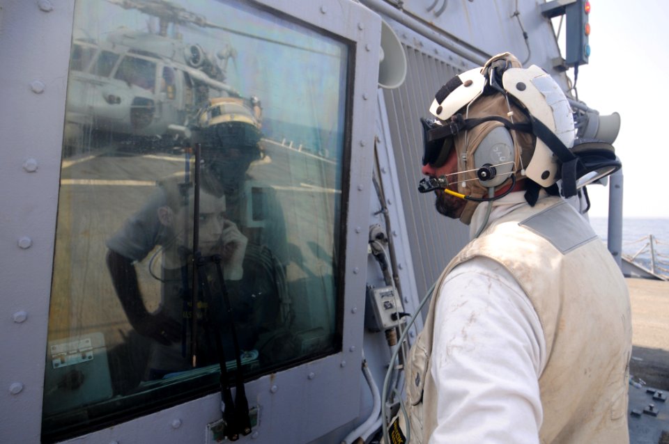 US Navy 110728-N-XQ375-218 Boatswain's Mate 1st Class Dave Mullins, right, stands by as Lt. j.g. Ken Kerr communicates with the pilots of an MH-60S