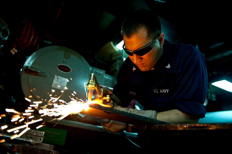 US Navy 110803-N-BT887-204 Hull Technician 3rd Class Jeffrey Meginness, from Modesto, Calif., cuts sheet metal with an acetylene torch aboard the N