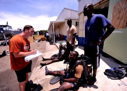 US Navy 110729-N-KB666-092 Master Seaman John Penney, left, onducts pre-dive checks with Ordinary Seaman Kemar Smith, sitting left, Petty Officer D photo