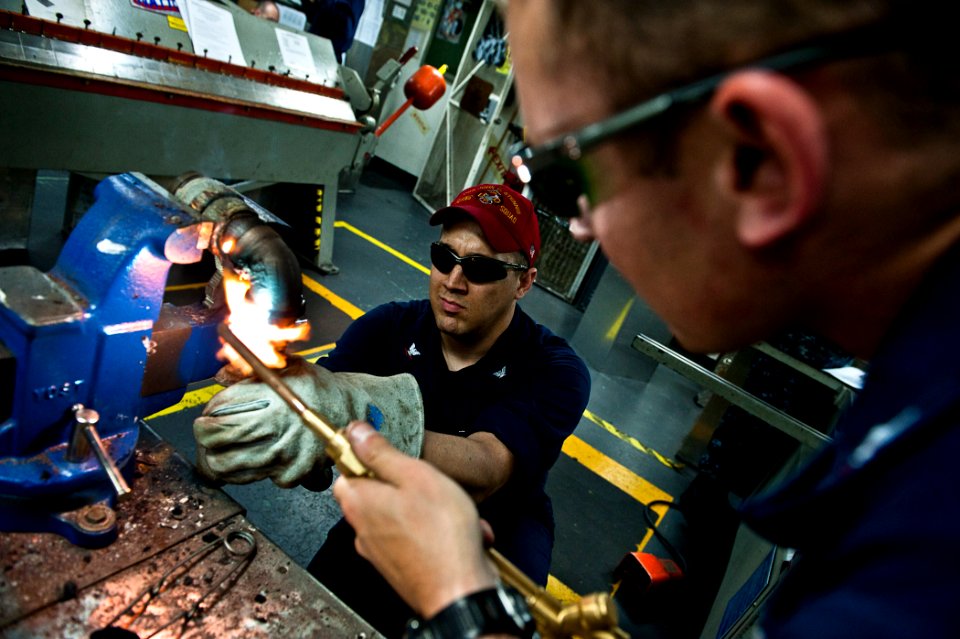 US Navy 110803-N-BT887-083 Hull Technician 3rd Class Jeffrey Meginness, from Modesto, Calif., removes a ring from a pipe while Hull Technician 2nd