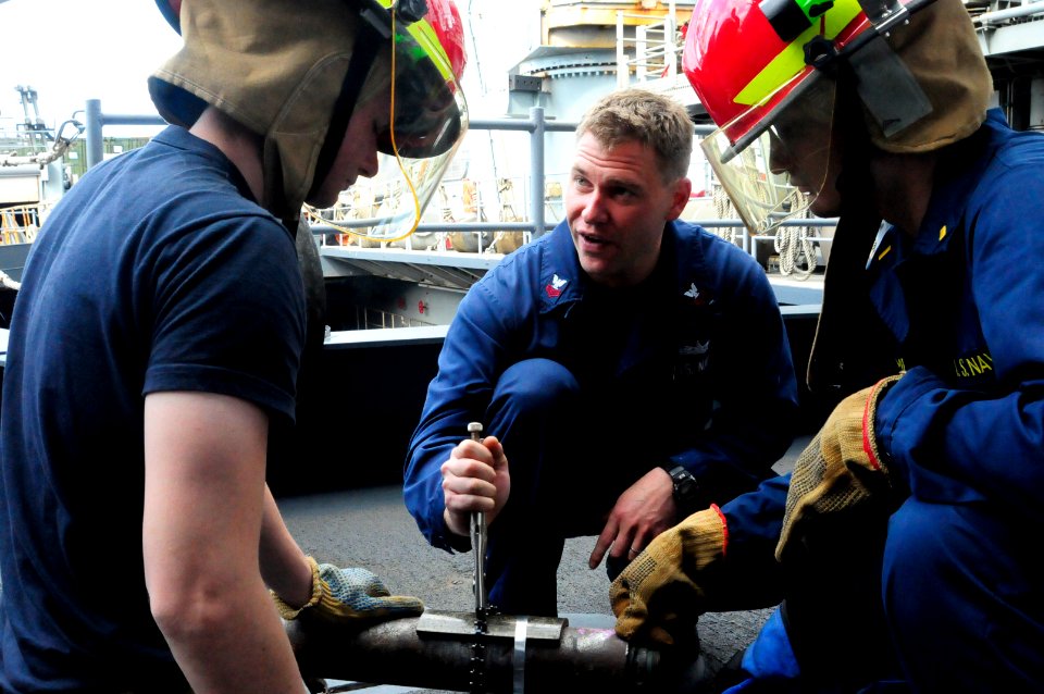 US Navy 110729-N-WV964-106 Damage Controlman 1st Class Kevin Clark instructs Sailors how to apply a banding strip to a pipe during basic damage con