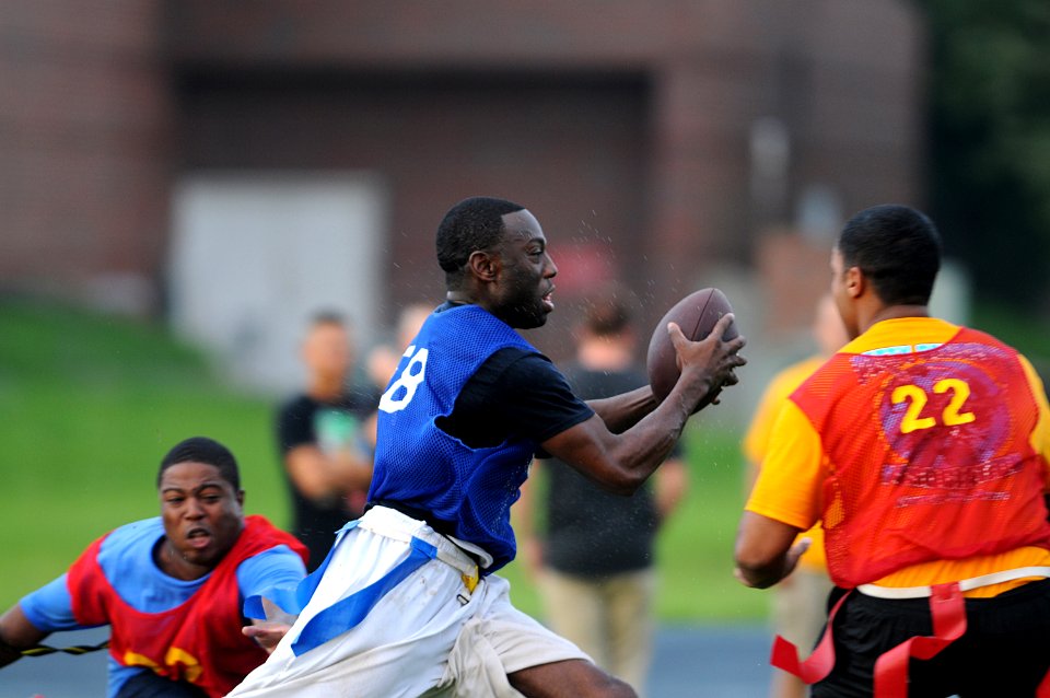 US Navy 110802-N-GS507-523 Chief Information Systems Technician Otis Frazier, center, runs for a first down during the annual flag football game be
