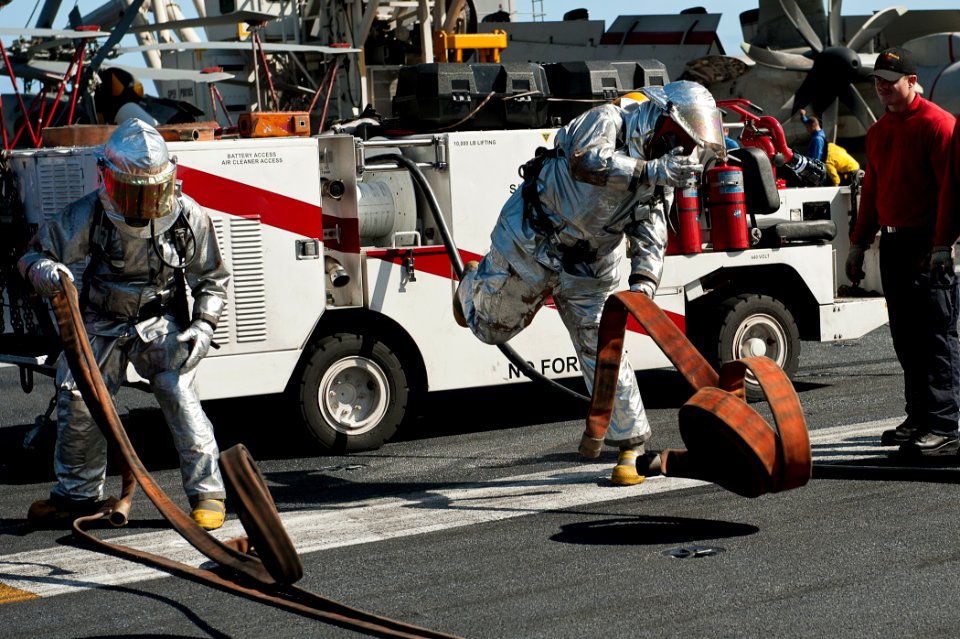 US Navy 110805-N-BT887-352 Aviation Boatswain's Mate Airman Kyle Busch and Aviation Boatswain's Mate Airman Bryan Bowers unravel a firefighting hos