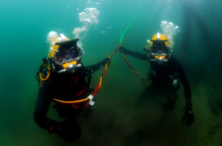 US Navy 110804-N-XD935-069 Navy Diver 3rd Class Bryan Myers, left, and Diver Leading Seaman Richard Nicholson take strain on their dive umbilical c photo