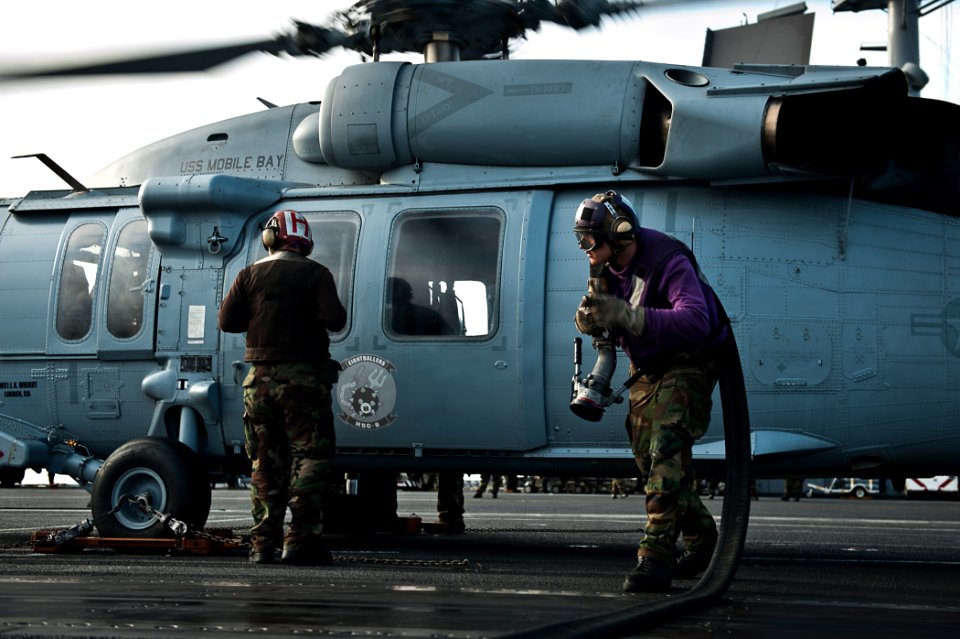 US Navy 110808-N-BT887-087 Airman Alexander Filipponi carries a refueling hose after filling an MH-60S Sea Hawk helicopter