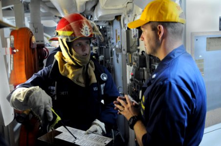 US Navy 110809-N-QL471-047 Damage Controlman Fireman Clayton Hatchett, left, reports the status of a simulated fire aboard the guided-missile destr