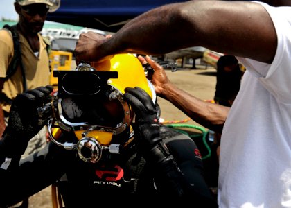 US Navy 110804-N-KB666-102 Able Body Seaman Howick Christie, right, assists Navy Diver 3rd Class Bryan Myers, center, as Lt. j.g. Peter Wilson-Kell photo