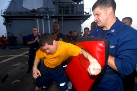 US Navy 110806-N-DU438-658 Interior Communications Electrician 2nd Class Aaron Aguilera, left, punches a bag held by Electronics Technician 3rd Cla