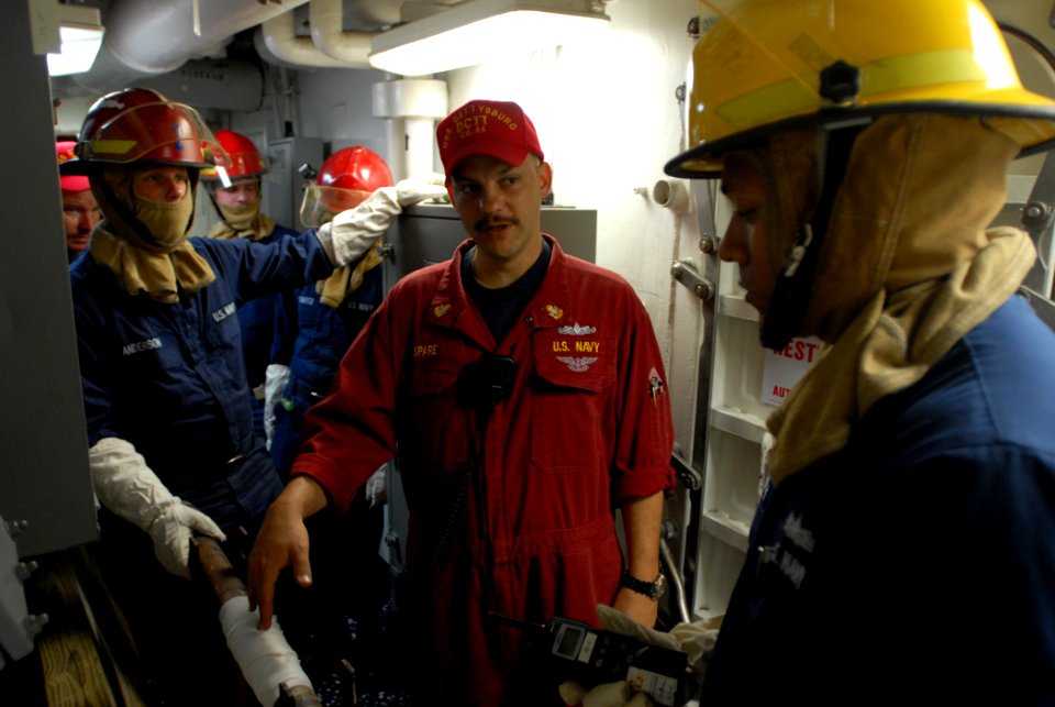 US Navy 110809-N-DU438-139 Chief Damage Controlman Timothy Spare, center, debriefs a fire party team after a damage control drill
