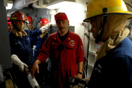 US Navy 110809-N-DU438-139 Chief Damage Controlman Timothy Spare, center, debriefs a fire party team after a damage control drill